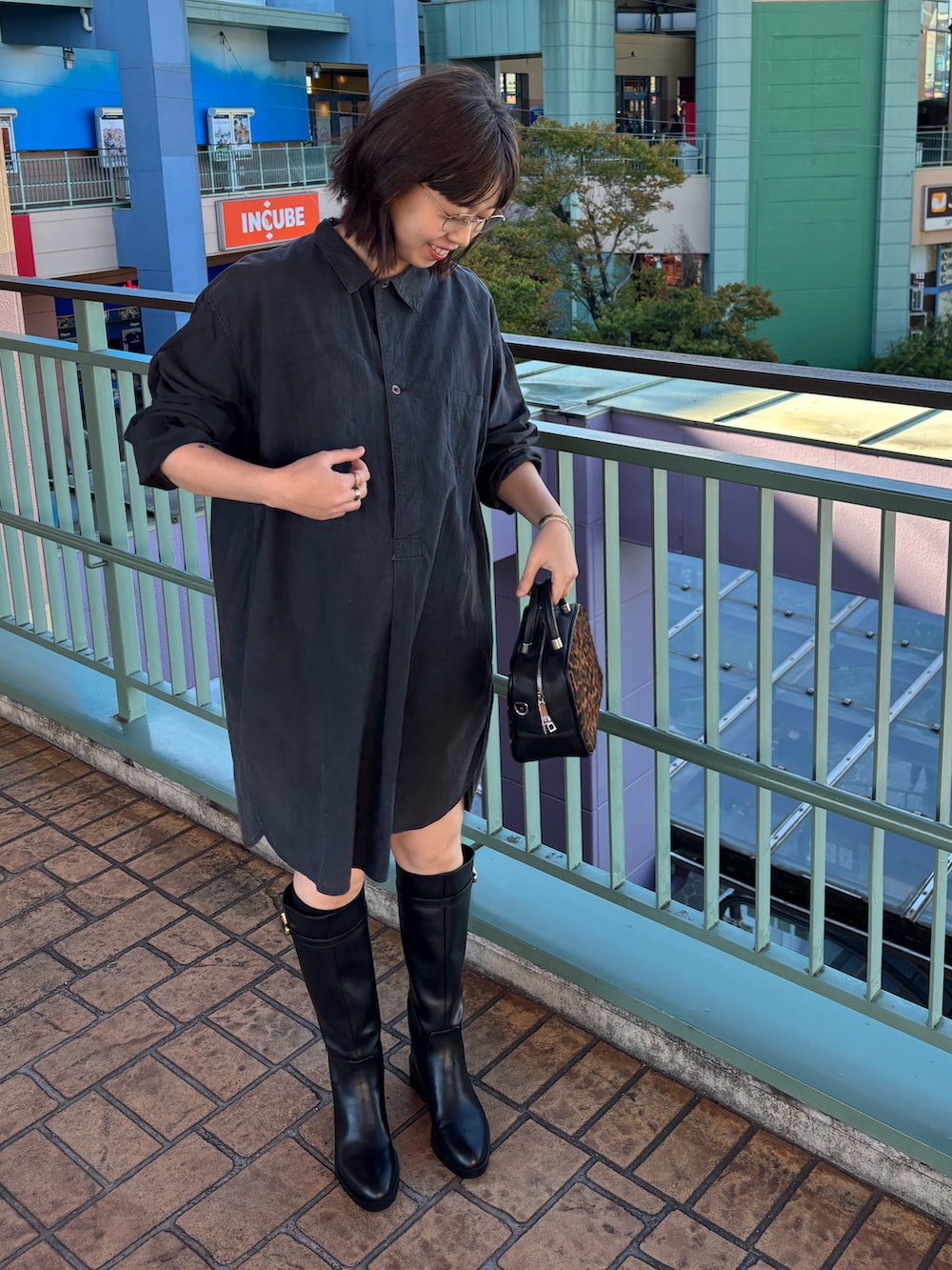 ブラック系のブーツ、ゴールド系のメガネを着用したレディースの秋コーディネートの4枚目の写真