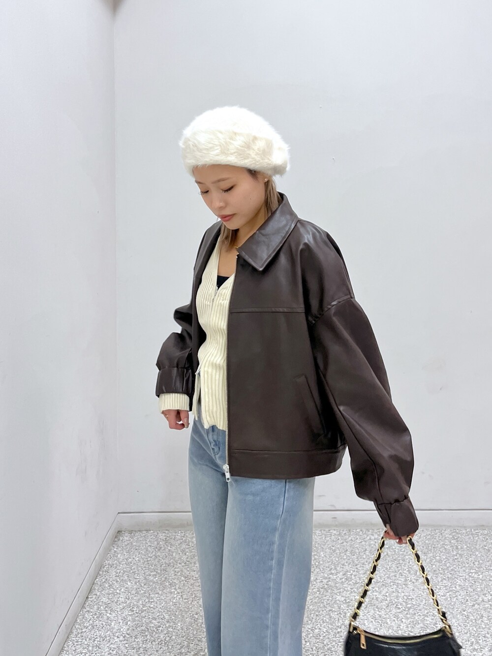 ブラウン系のライダースジャケット、ホワイト系のニット/セーター、ブラック系のブーツを着用したレディースの秋コーディネートの3枚目の写真