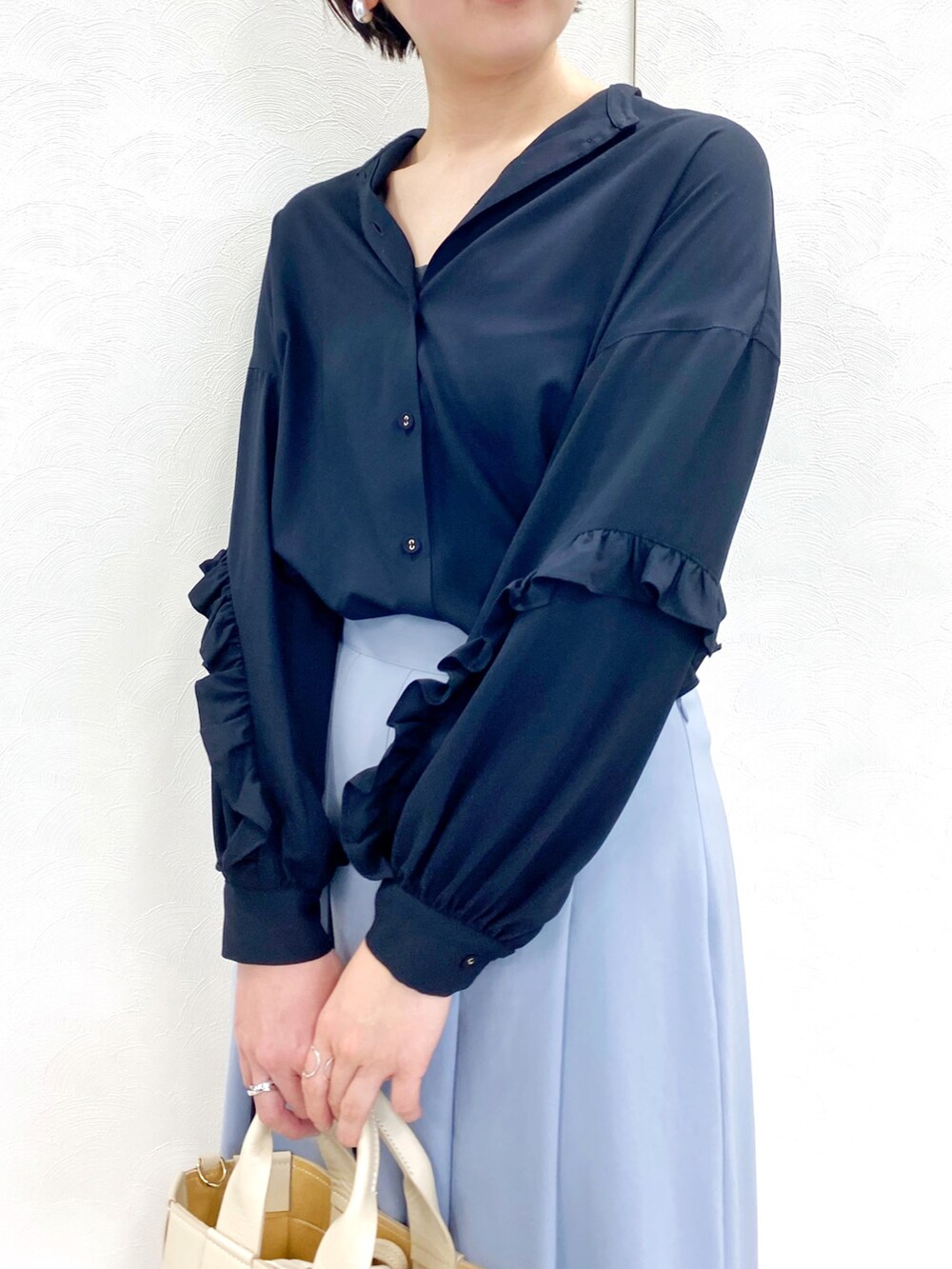 ブラック系のシャツ/ブラウス、ブルー系のスカート、ベージュ系のバッグを着用したレディースの冬コーディネートの3枚目の写真