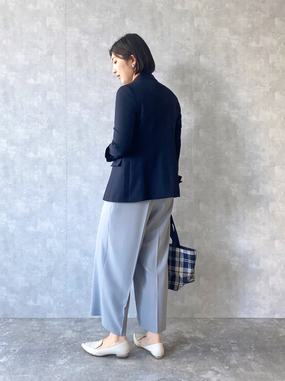 ブルー系のジャケット/アウター、グレー系のパンツ、ベージュ系のニット/セーターを着用したレディースの春コーディネートの2枚目の写真