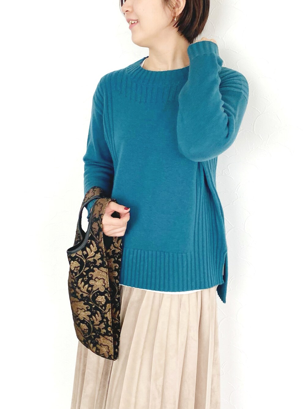 グリーン系のニット/セーター、ベージュ系のスカート、ブラック系のブーツを着用したレディースの秋コーディネートの2枚目の写真