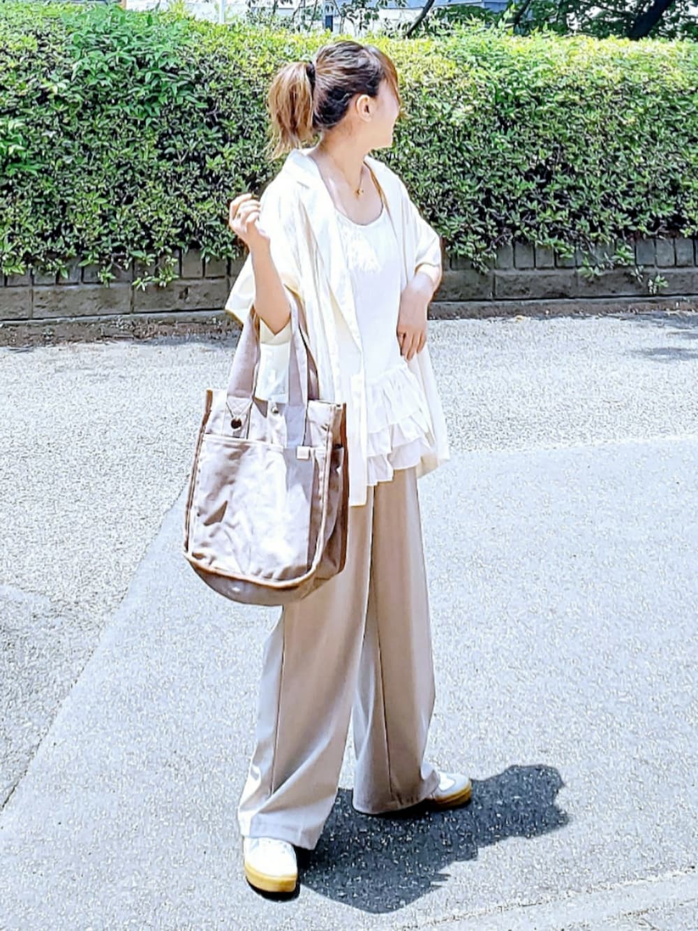 ホワイト系のテーラードジャケット、ホワイト系のキャミソール、ベージュ系のパンツを着用したレディースの夏コーディネートの2枚目の写真