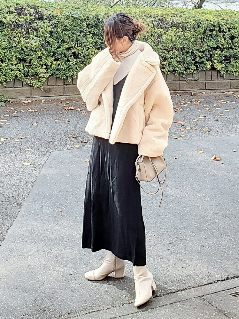 ホワイト系のピーコート、ブラック系のワンピース、ベージュ系のショルダーバッグを着用したレディースの冬コーディネートの2枚目の写真