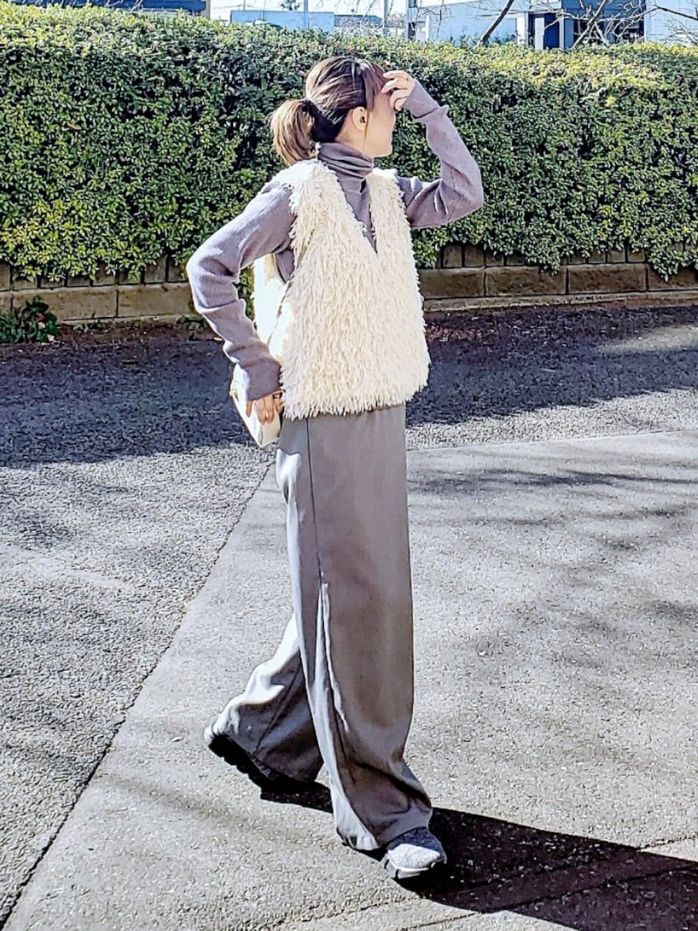 グレー系のニット/セーター、ホワイト系のベスト、グレー系のスラックスを着用したレディースの冬コーディネートの2枚目の写真