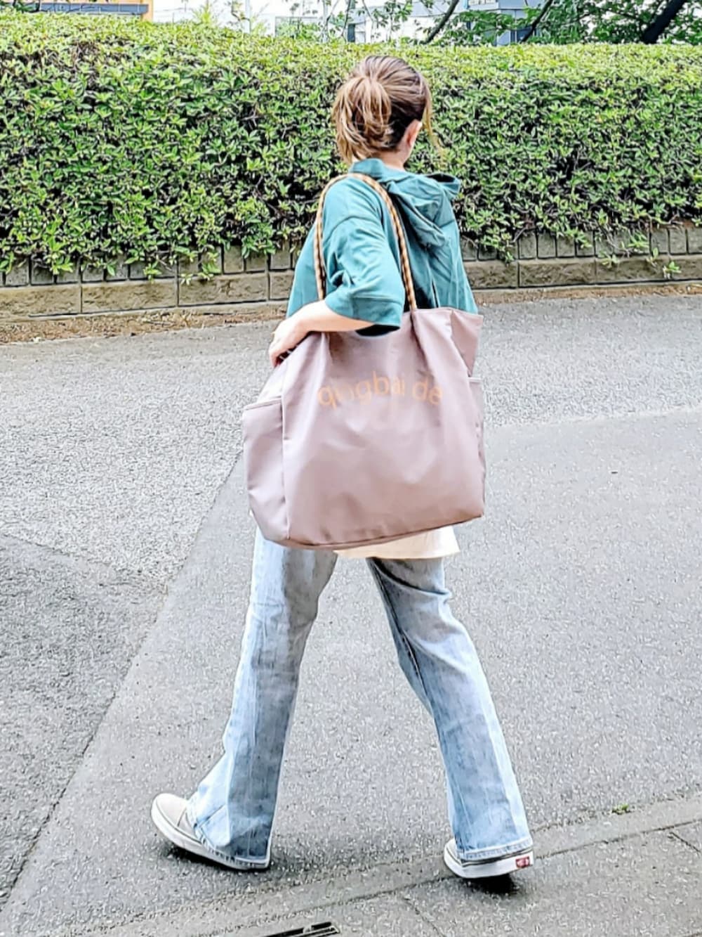 グレー系のトートバッグ、グリーン系のパーカー、ブルー系のデニムパンツを着用したレディースの夏コーディネートの3枚目の写真