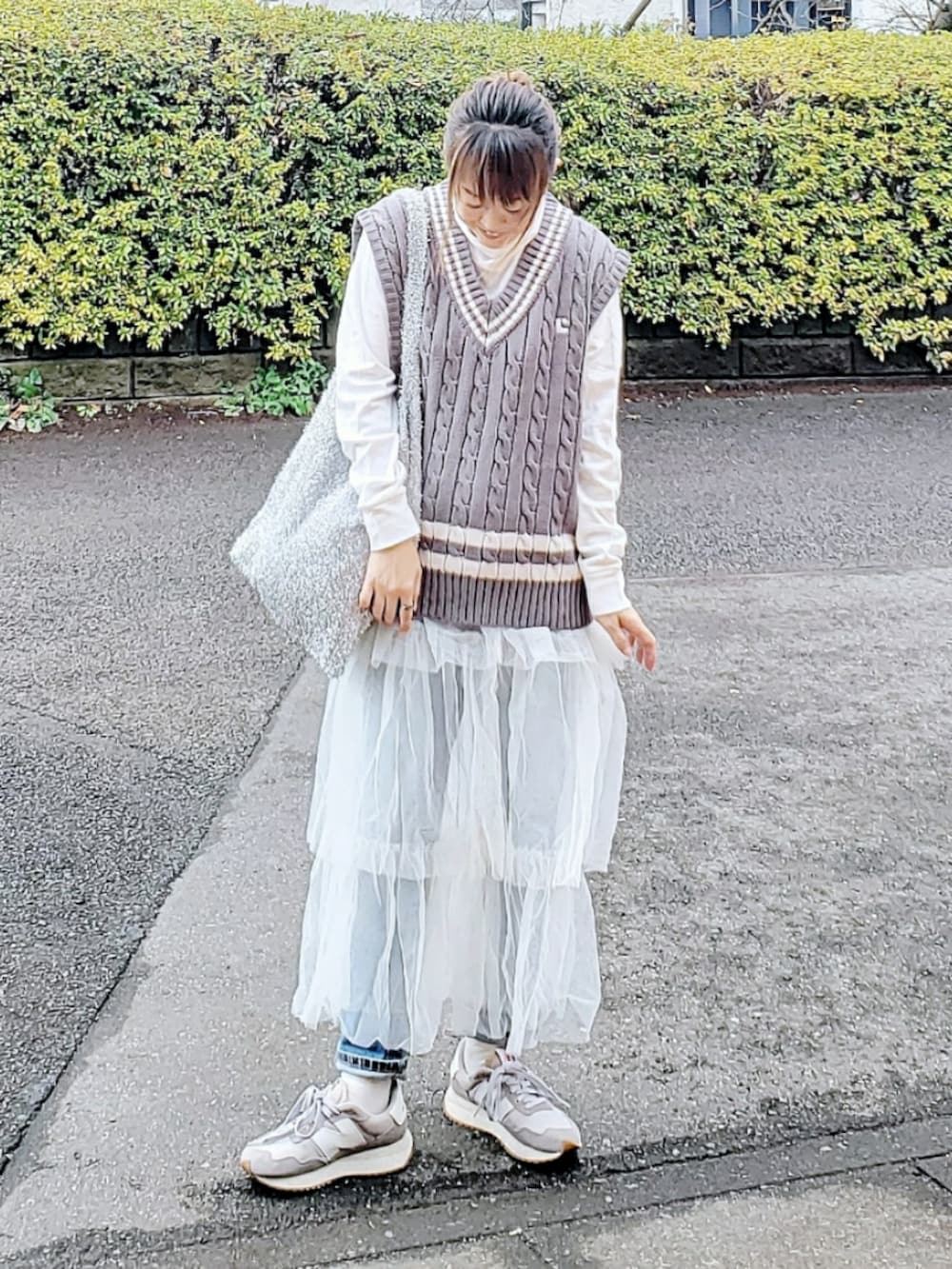 グレー系のベスト、ホワイト系のスカート、ブルー系のデニムパンツを着用したレディースの春コーディネートの3枚目の写真