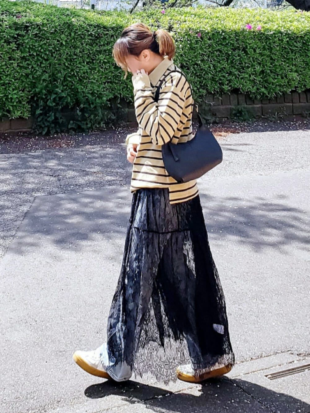 イエロー系のTシャツ/カットソー、ブラック系のスカート、ブルー系のデニムパンツを着用したレディースの春コーディネートの2枚目の写真