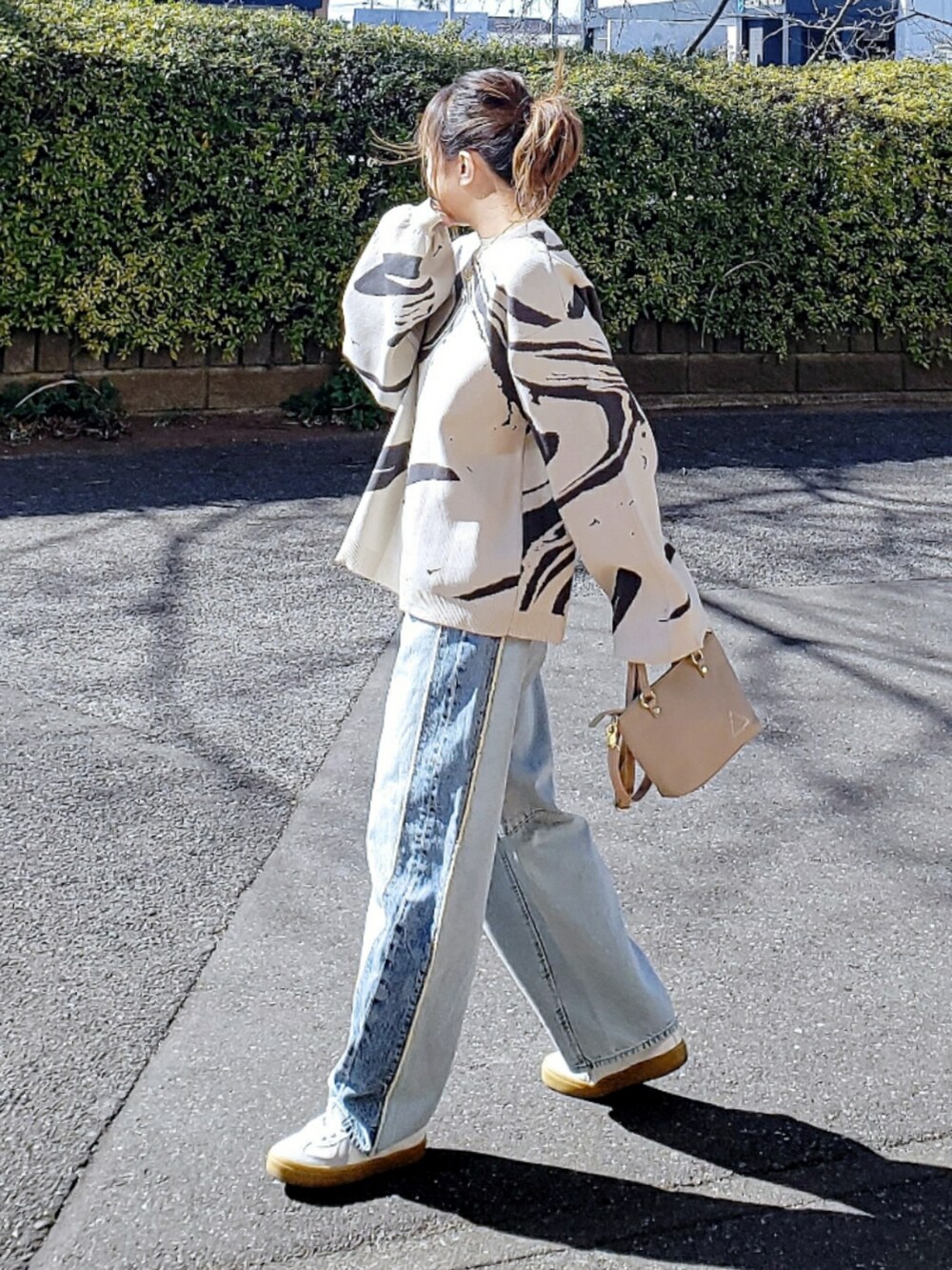 ホワイト系のニット/セーター、ブルー系のデニムパンツ、ベージュ系のショルダーバッグを着用したレディースの冬コーディネートの3枚目の写真