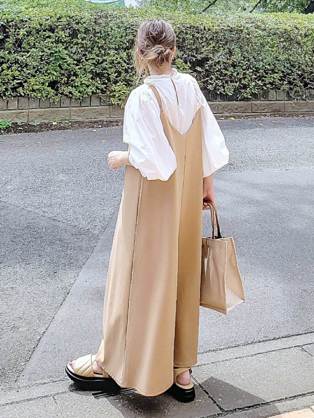 ベージュ系のジャンパースカート、ベージュ系のシャツ/ブラウス、ベージュ系のかごバッグを着用したレディースの秋コーディネートの2枚目の写真