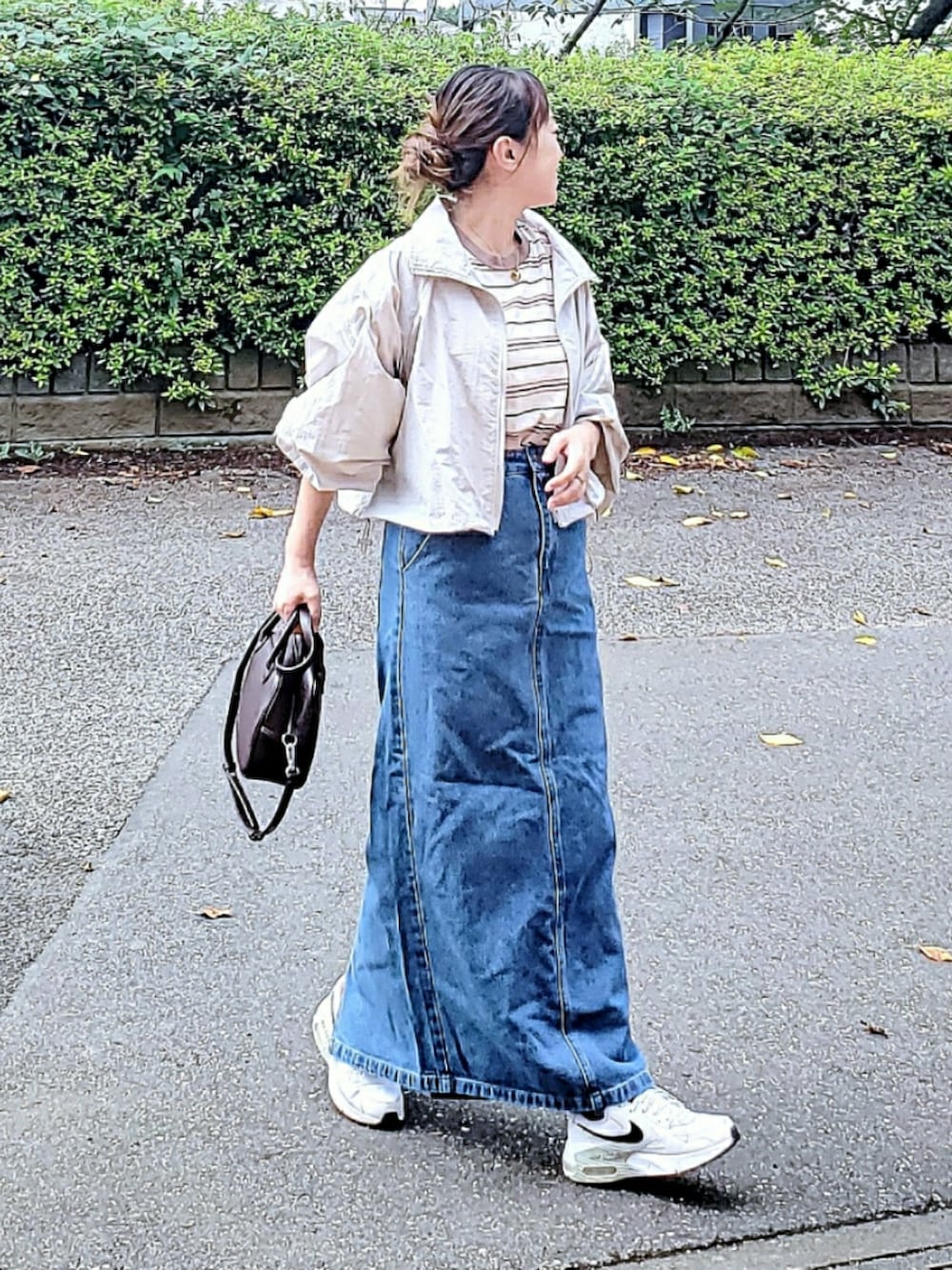 グレー系のナイロンジャケット、ブルー系のデニムスカート、ホワイト系のTシャツ/カットソーを着用したレディースの秋コーディネートの3枚目の写真