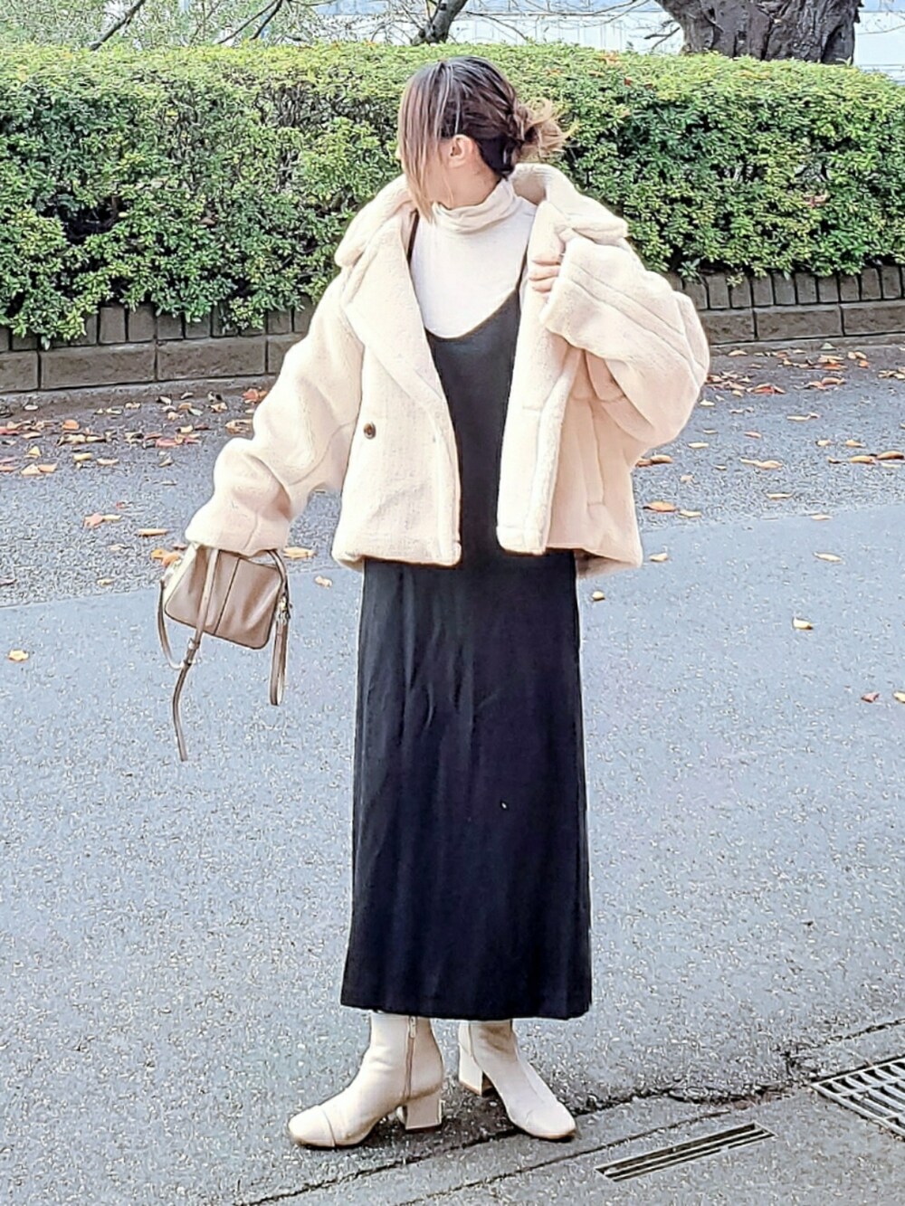ホワイト系のピーコート、ブラック系のワンピース、ベージュ系のショルダーバッグを着用したレディースの冬コーディネートの3枚目の写真