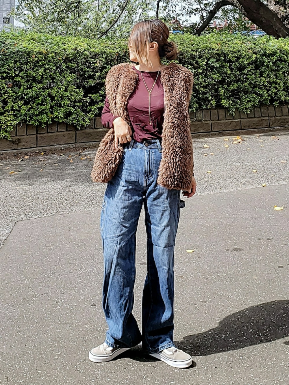 ブルー系のデニムパンツ、ブラウン系のベスト、ブラウン系のTシャツ/カットソーを着用したレディースの秋コーディネートの2枚目の写真