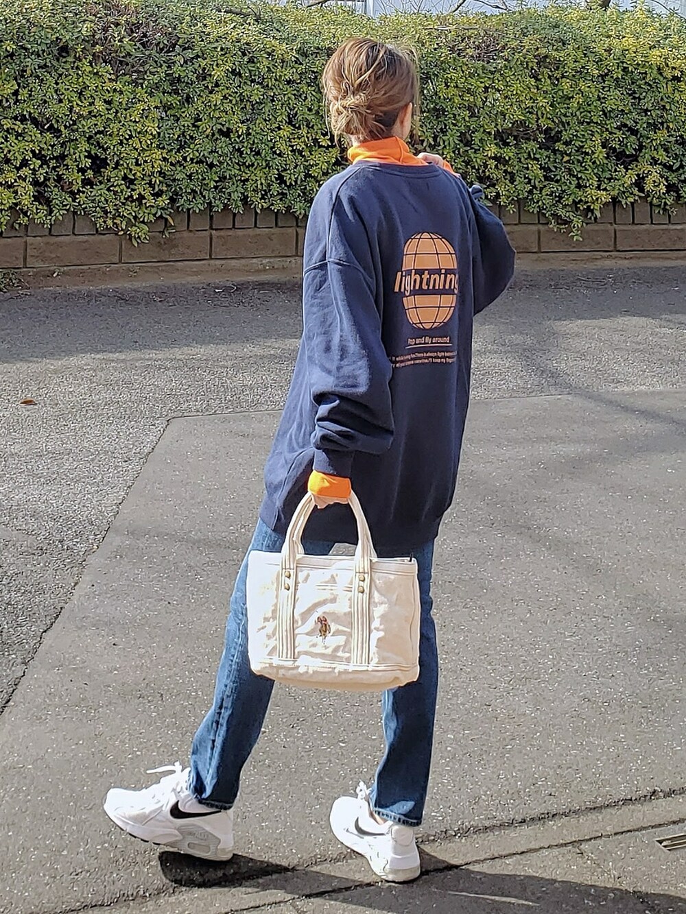 ホワイト系のトートバッグ、ブルー系のスウェット、オレンジ系のTシャツ/カットソーを着用したレディースの冬コーディネートの2枚目の写真