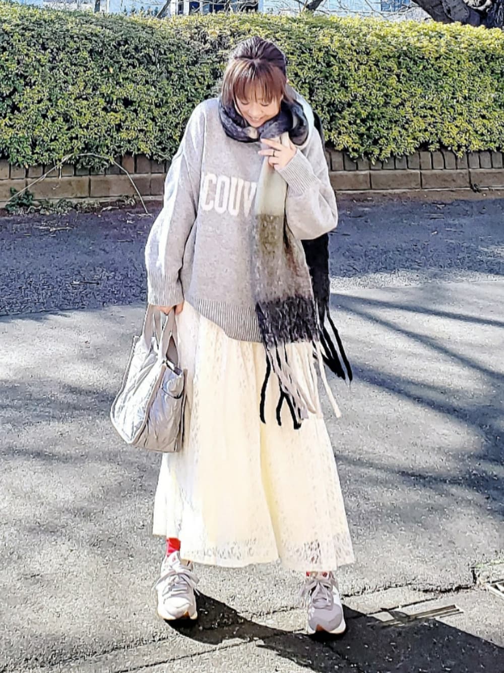 グレー系のニット/セーター、ホワイト系のスカート、グレー系のトートバッグを着用したレディースの冬コーディネートの2枚目の写真