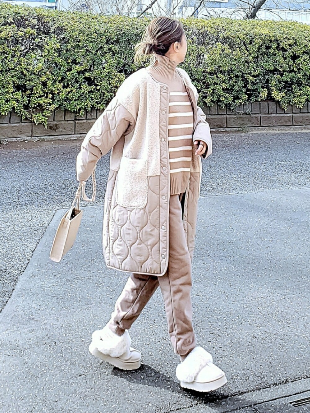 ホワイト系のその他アウター、ベージュ系のニット/セーター、ベージュ系のスウェットパンツを着用したレディースの冬コーディネートの3枚目の写真