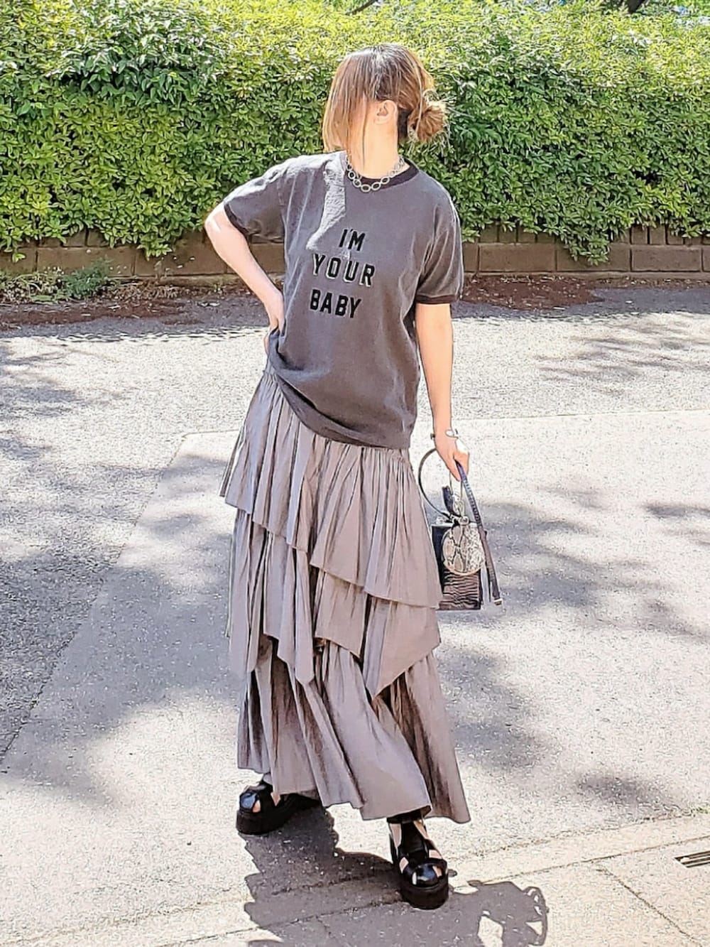 ブラック系のTシャツ/カットソー、グレー系のスカート、ブラック系のサンダルを着用したレディースの春コーディネートの2枚目の写真