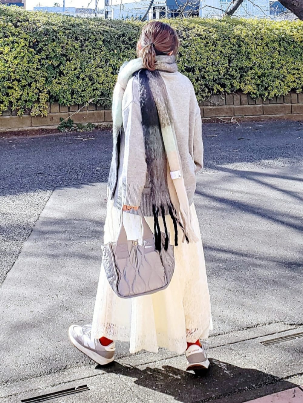 グレー系のニット/セーター、ホワイト系のスカート、グレー系のトートバッグを着用したレディースの冬コーディネートの3枚目の写真