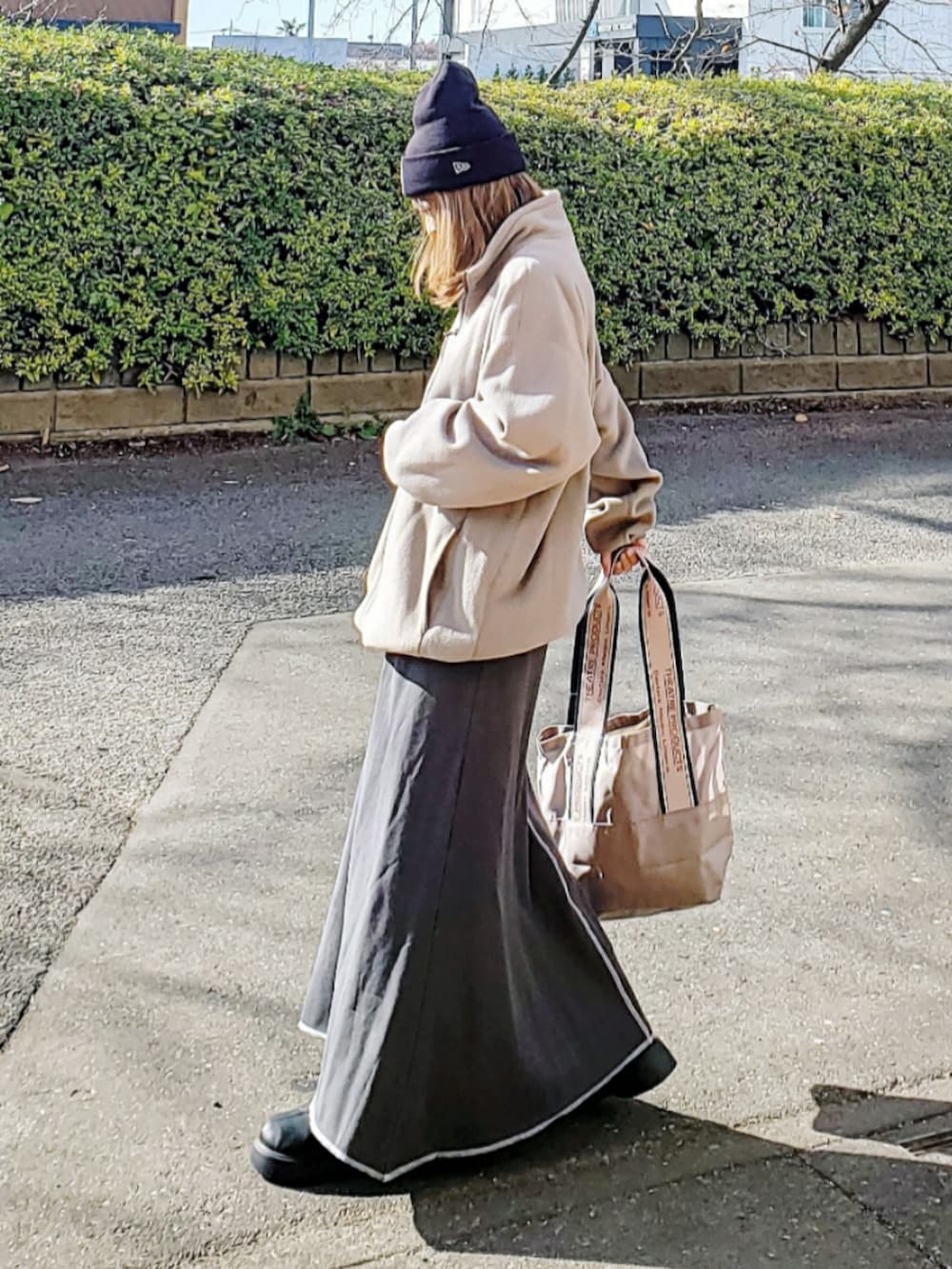 ブラウン系のトップス、グレー系のスカート、ベージュ系のトートバッグを着用したレディースの冬コーディネートの3枚目の写真