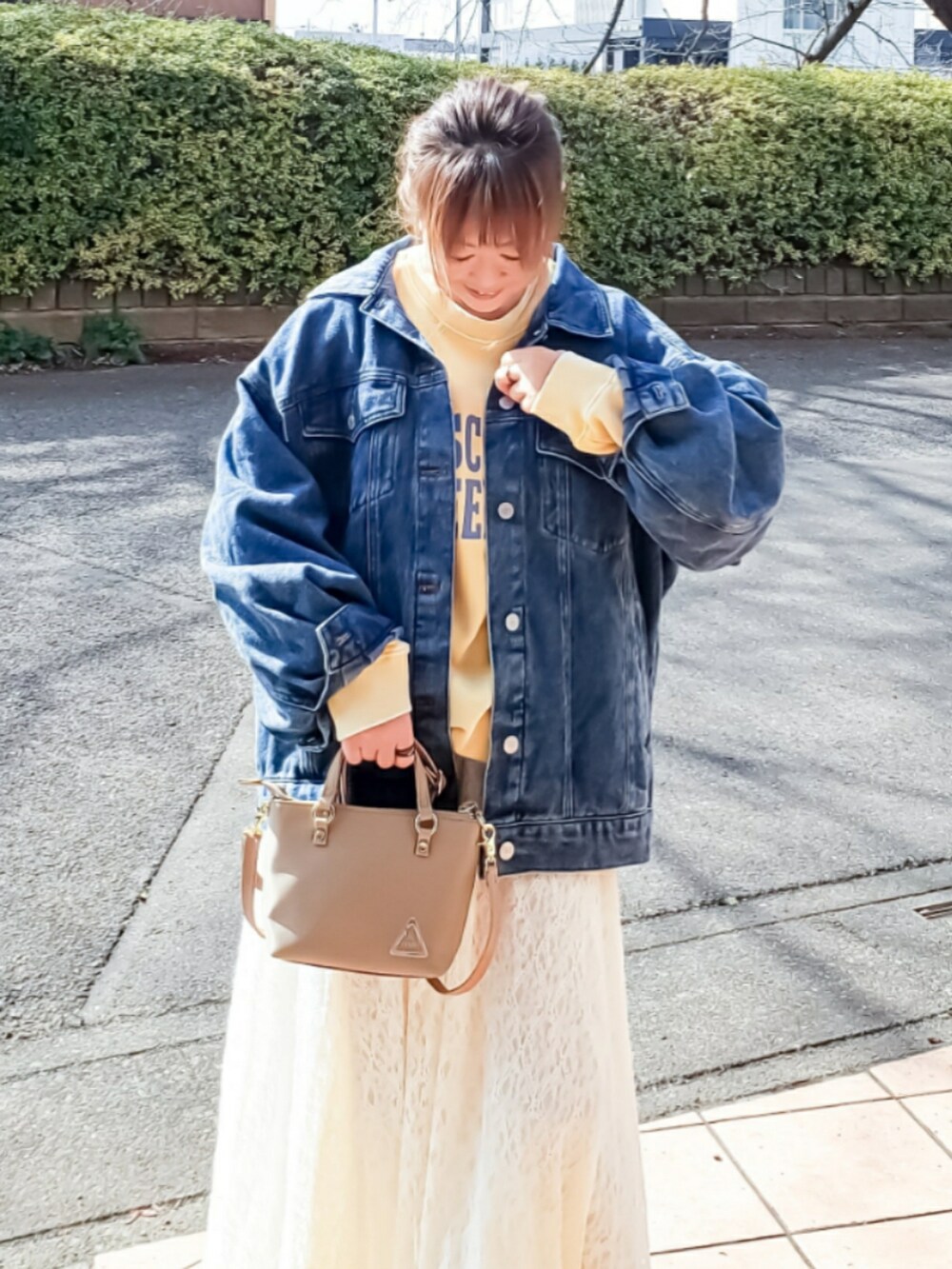 ブルー系のデニムジャケット、イエロー系のスウェット、ホワイト系のスカートを着用したレディースの春コーディネートの4枚目の写真