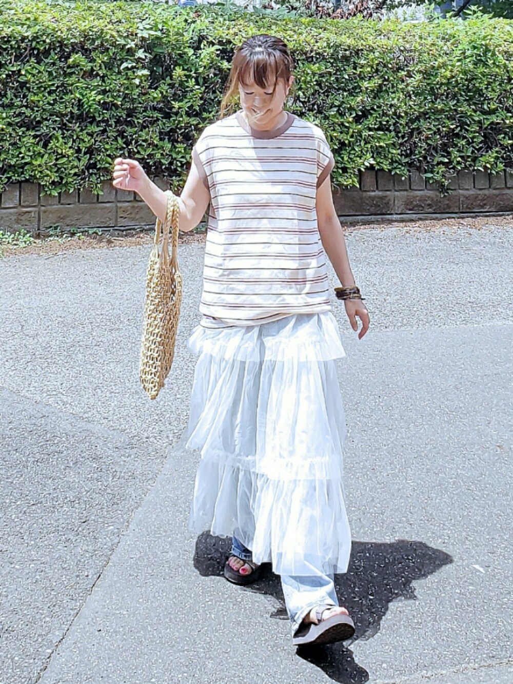 ホワイト系のTシャツ/カットソー、ホワイト系のスカート、ブルー系のデニムパンツを着用したレディースの夏コーディネートの2枚目の写真