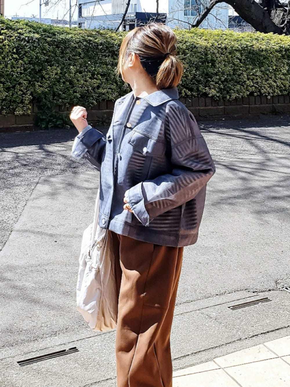 ブルー系のデニムジャケット、ブラック系のTシャツ/カットソー、ブラウン系のスウェットパンツを着用したレディースの春コーディネートの4枚目の写真