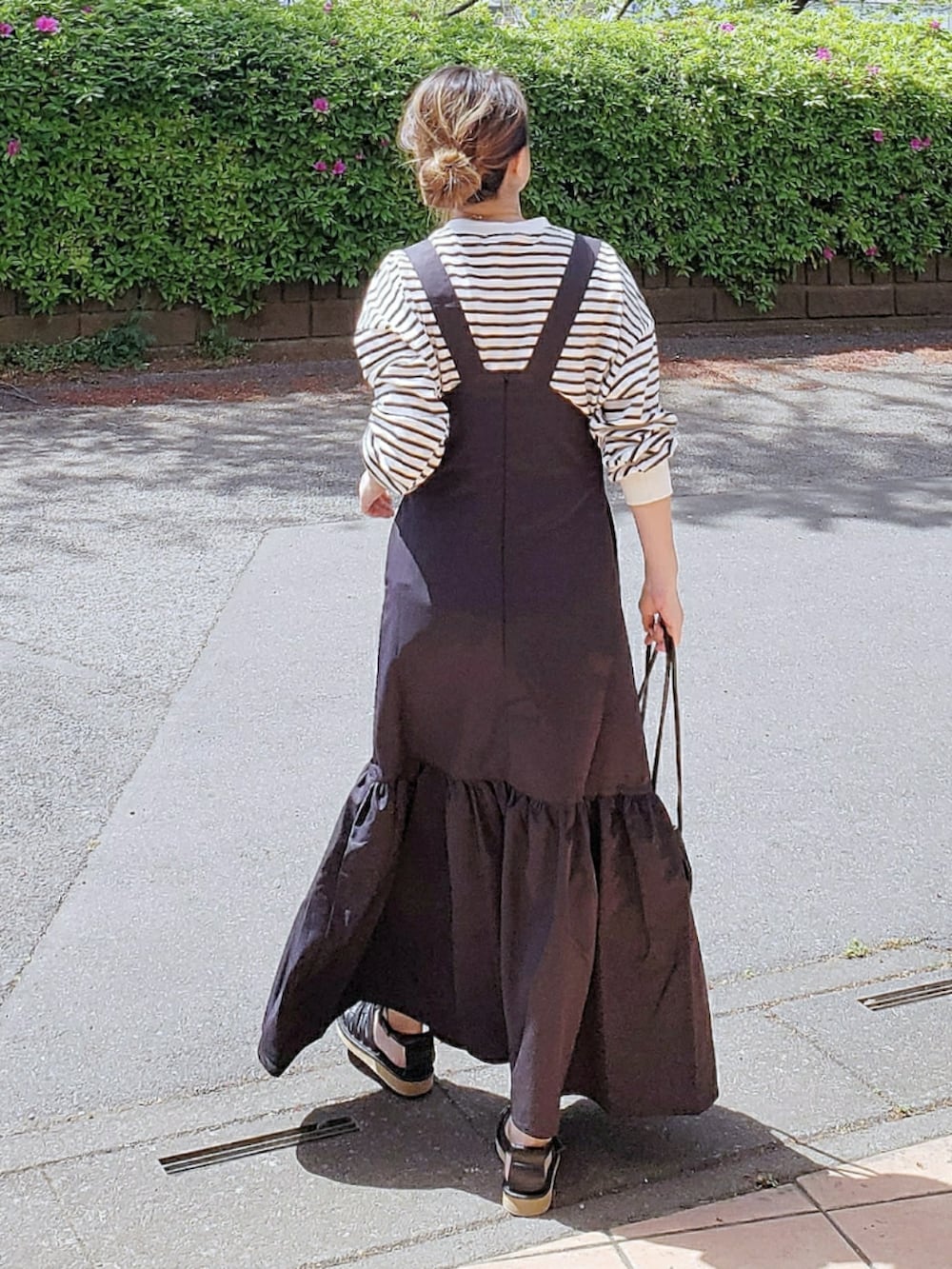 ブラック系のジャンパースカート、ブラック系のTシャツ/カットソー、ブラック系のサンダルを着用したレディースの春コーディネートの3枚目の写真