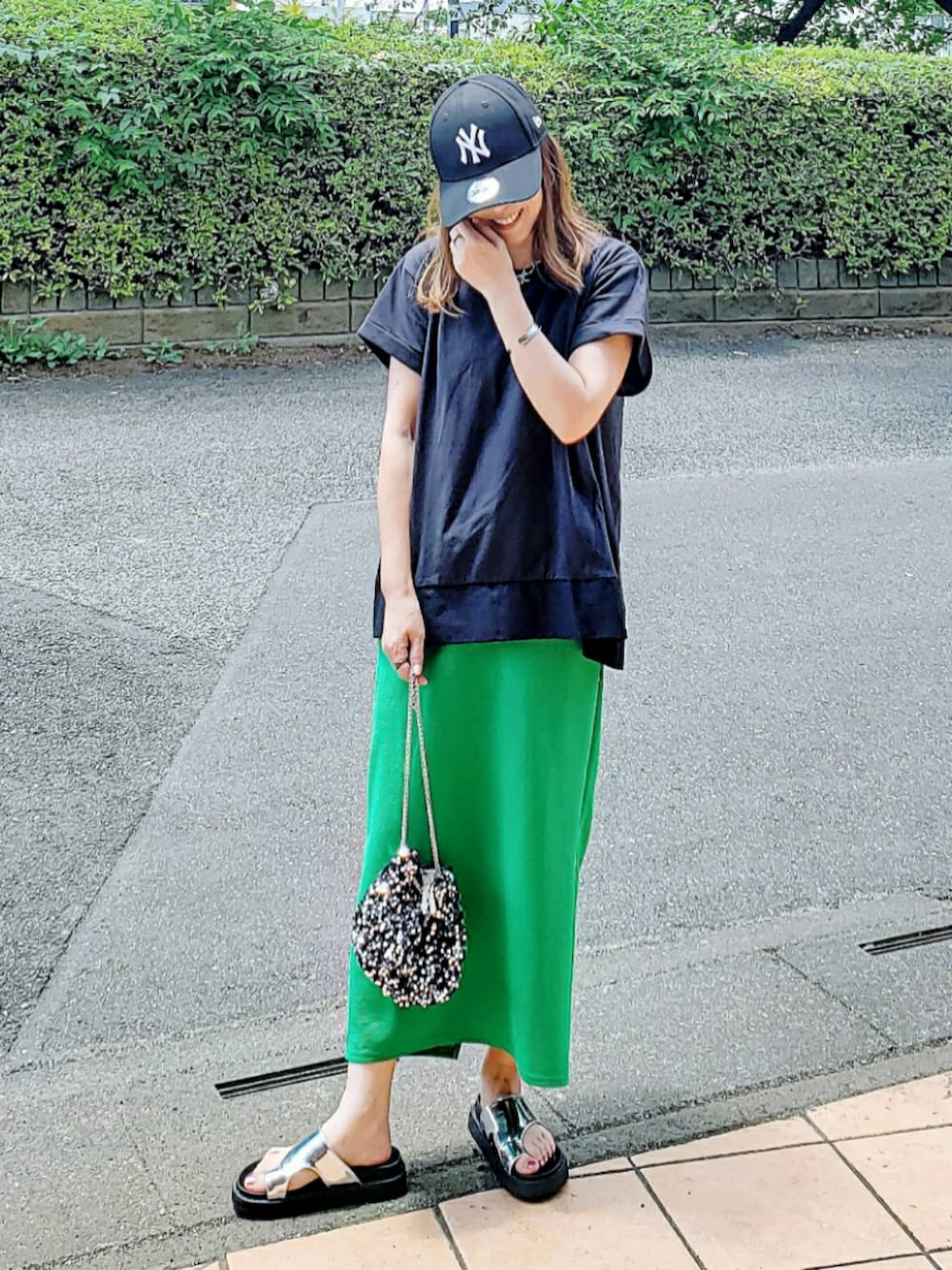 ブラック系のTシャツ/カットソー、グリーン系のスカート、シルバー系のサンダルを着用したレディースの夏コーディネートの2枚目の写真