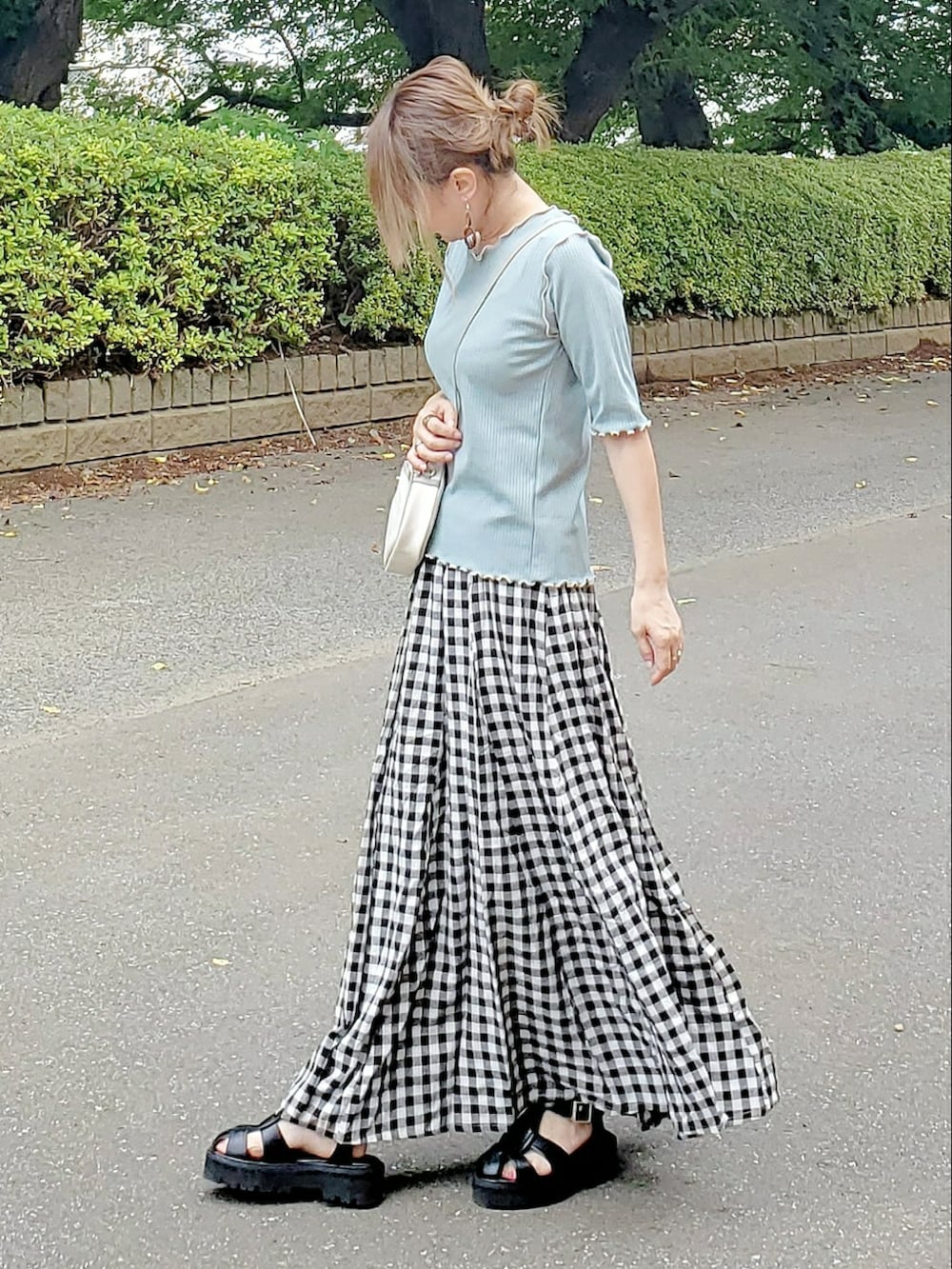 グリーン系のTシャツ/カットソー、ブラック系のスカート、ブラック系のサンダルを着用したレディースの夏コーディネートの2枚目の写真