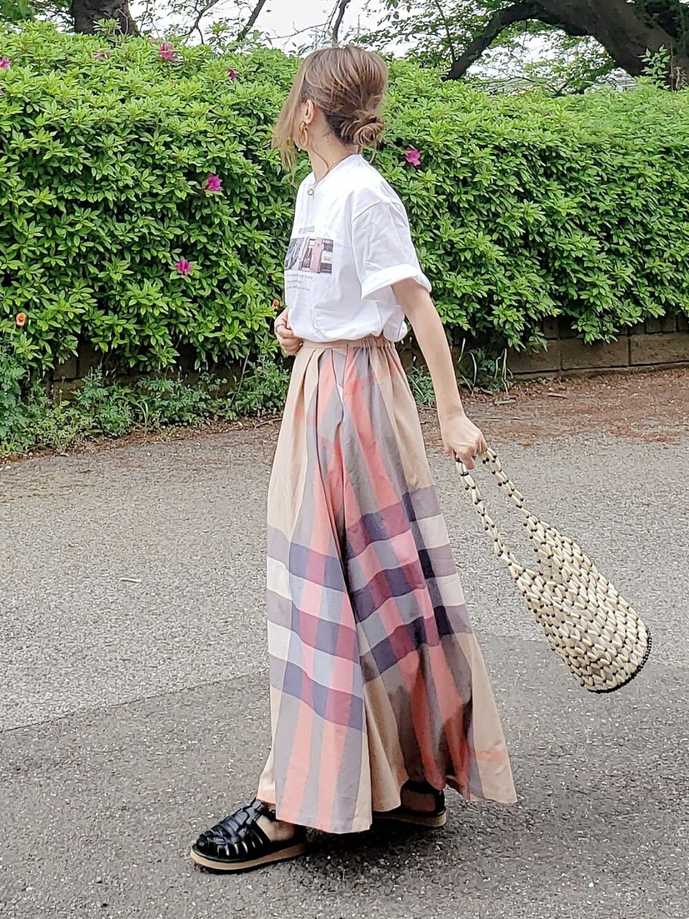 ホワイト系のTシャツ/カットソー、ベージュ系のスカート、ブラック系のサンダルを着用したレディースの春コーディネートの2枚目の写真
