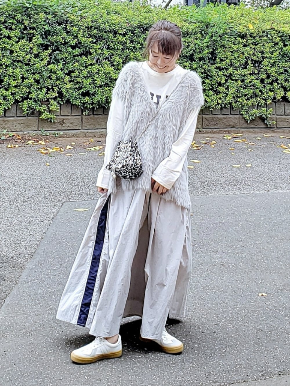 グレー系のベスト、ホワイト系のTシャツ/カットソー、グレー系のスカートを着用したレディースの秋コーディネートの2枚目の写真