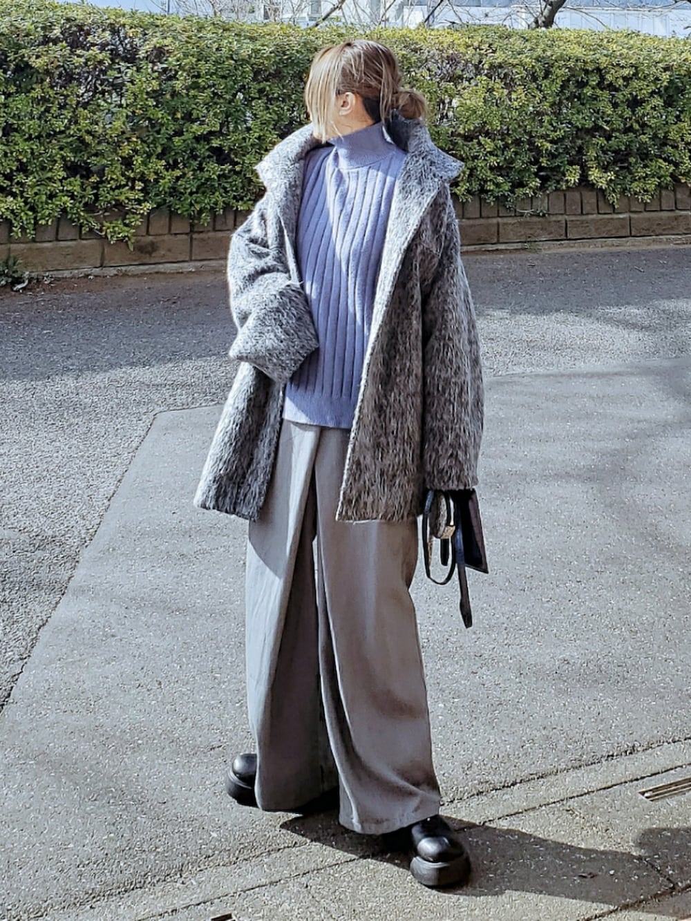 グレー系のジャケット/アウター、ブルー系のニット/セーター、グレー系のスラックスを着用したレディースの冬コーディネートの2枚目の写真