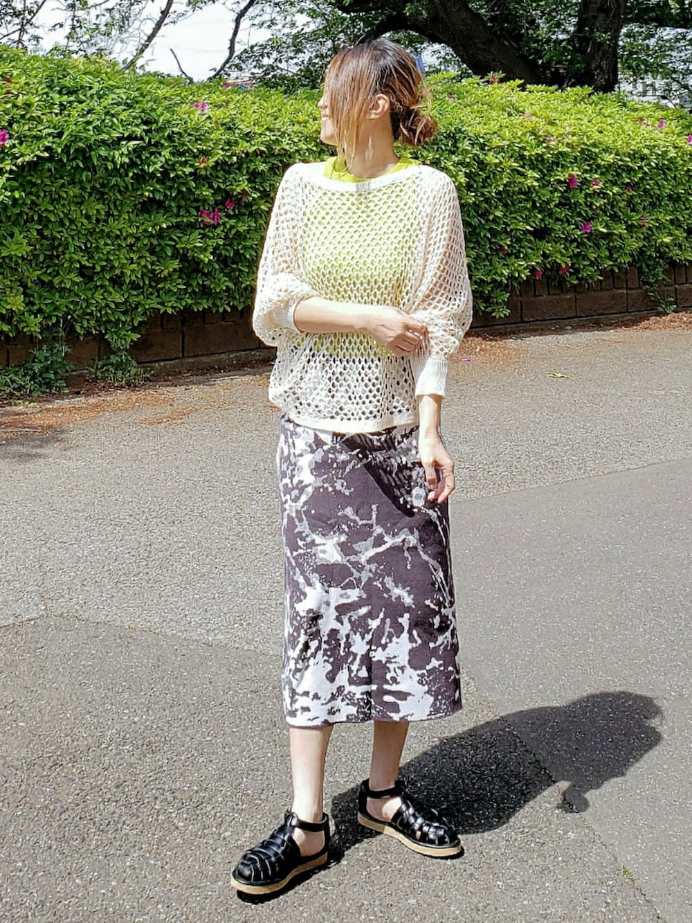 グリーン系のタンクトップ、ベージュ系のニット/セーター、グレー系のスカートを着用したレディースの春コーディネートの2枚目の写真