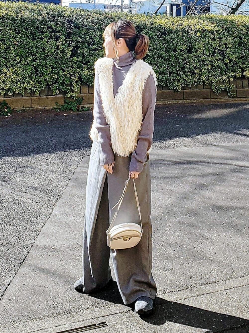 グレー系のニット/セーター、ホワイト系のベスト、グレー系のスラックスを着用したレディースの冬コーディネートの3枚目の写真