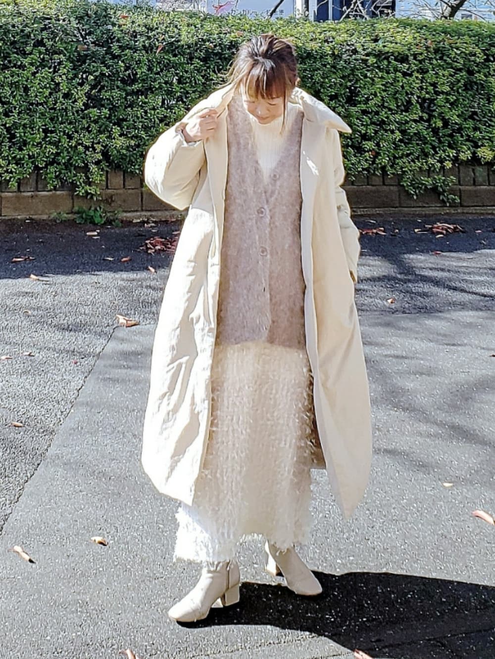 ベージュ系のダウンジャケット/コート、ブラウン系のカーディガン/ボレロ、ホワイト系のニット/セーターを着用したレディースの冬コーディネートの2枚目の写真