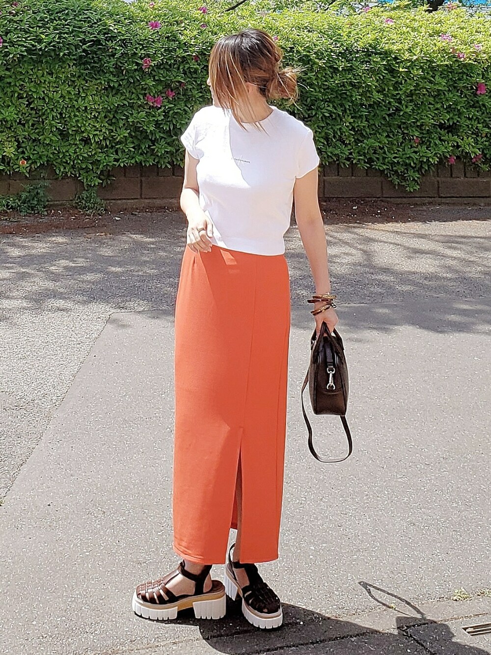 ホワイト系のTシャツ/カットソー、ブラウン系のサンダル、オレンジ系のスカートを着用したレディースの春コーディネートの2枚目の写真