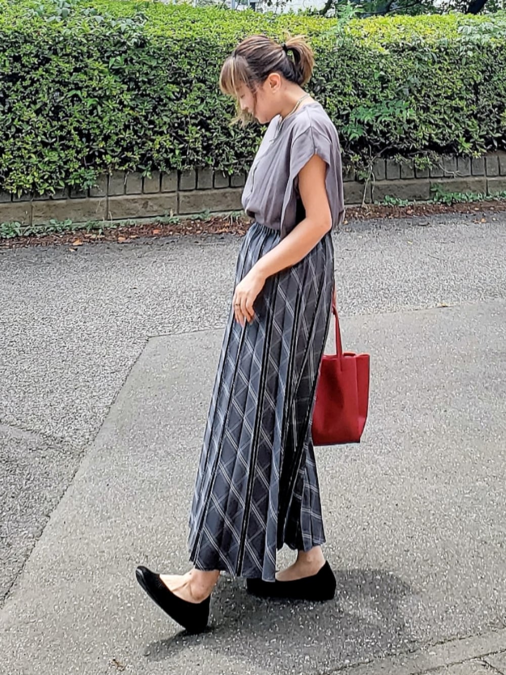 グレー系のスカート、グレー系のTシャツ/カットソー、レッド系のトートバッグを着用したレディースの夏コーディネートの3枚目の写真