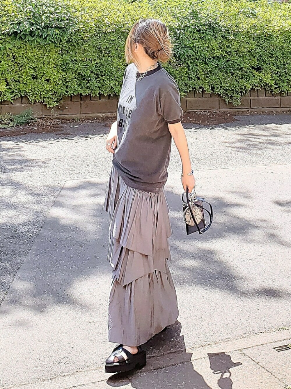 ブラック系のTシャツ/カットソー、グレー系のスカート、ブラック系のサンダルを着用したレディースの春コーディネートの3枚目の写真