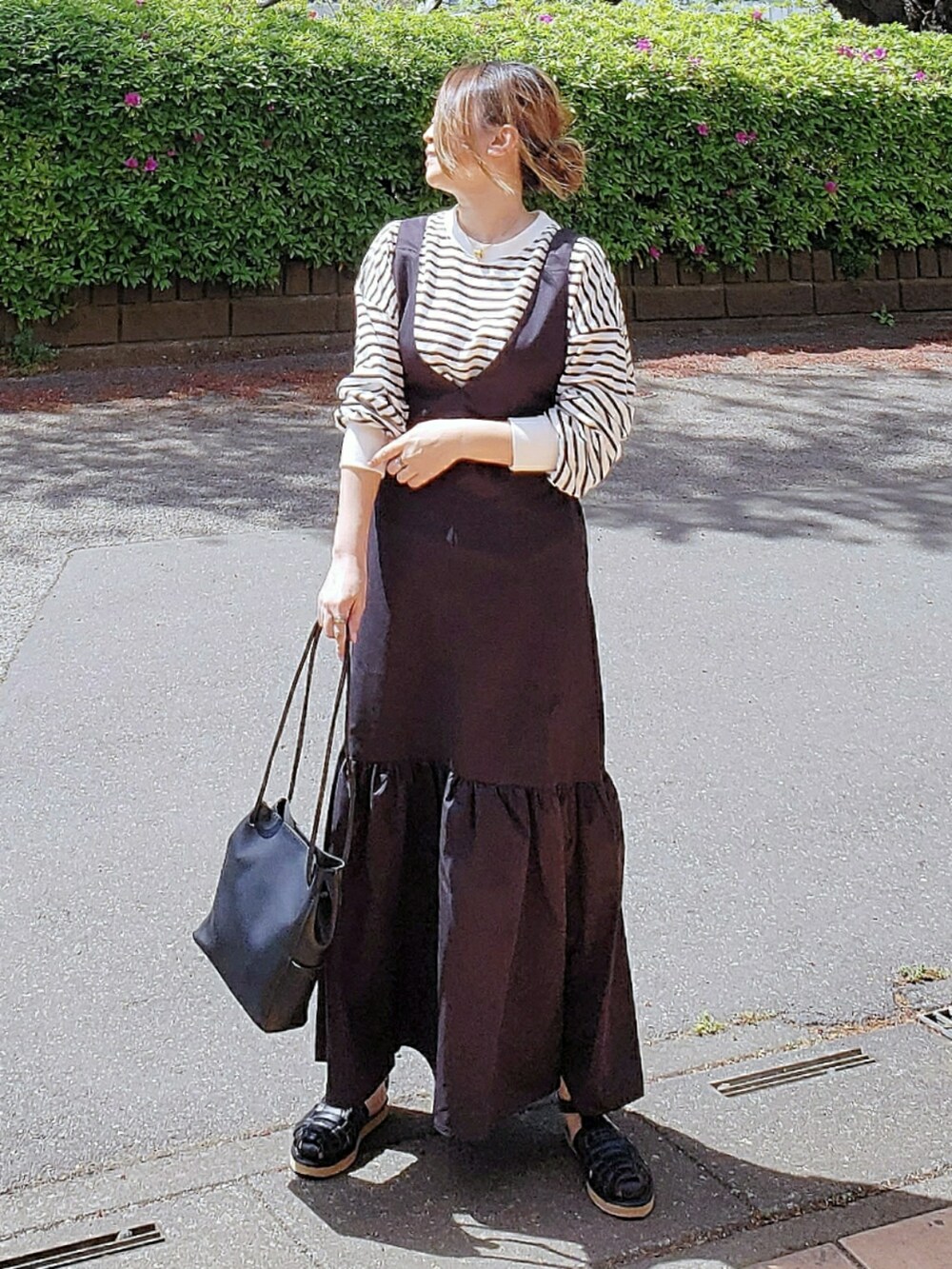 ブラック系のジャンパースカート、ブラック系のTシャツ/カットソー、ブラック系のサンダルを着用したレディースの春コーディネートの2枚目の写真