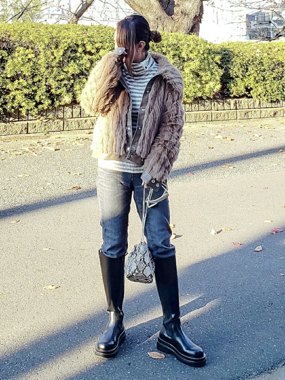 ブラウン系のブルゾン、グレー系のデニムパンツ、ブラック系のブーツを着用したレディースの冬コーディネートの2枚目の写真