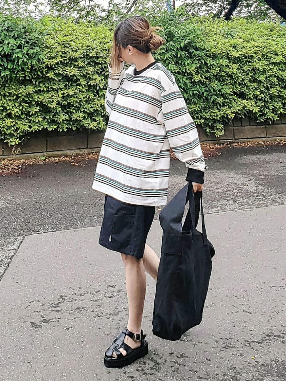 ブラック系のショルダーバッグ、ホワイト系のTシャツ/カットソー、ブラック系のパンツを着用したレディースの春コーディネートの2枚目の写真