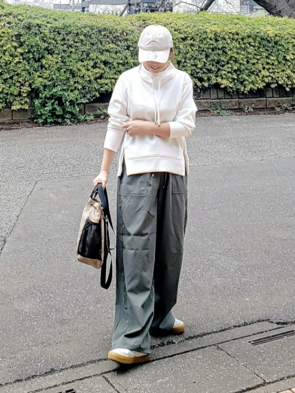グリーン系のカーゴパンツ、ホワイト系のスウェット、ベージュ系のショルダーバッグを着用したレディースの春コーディネートの3枚目の写真