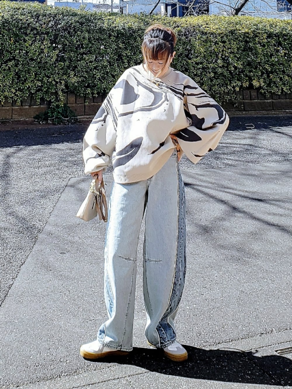 ホワイト系のニット/セーター、ブルー系のデニムパンツ、ベージュ系のショルダーバッグを着用したレディースの冬コーディネートの2枚目の写真