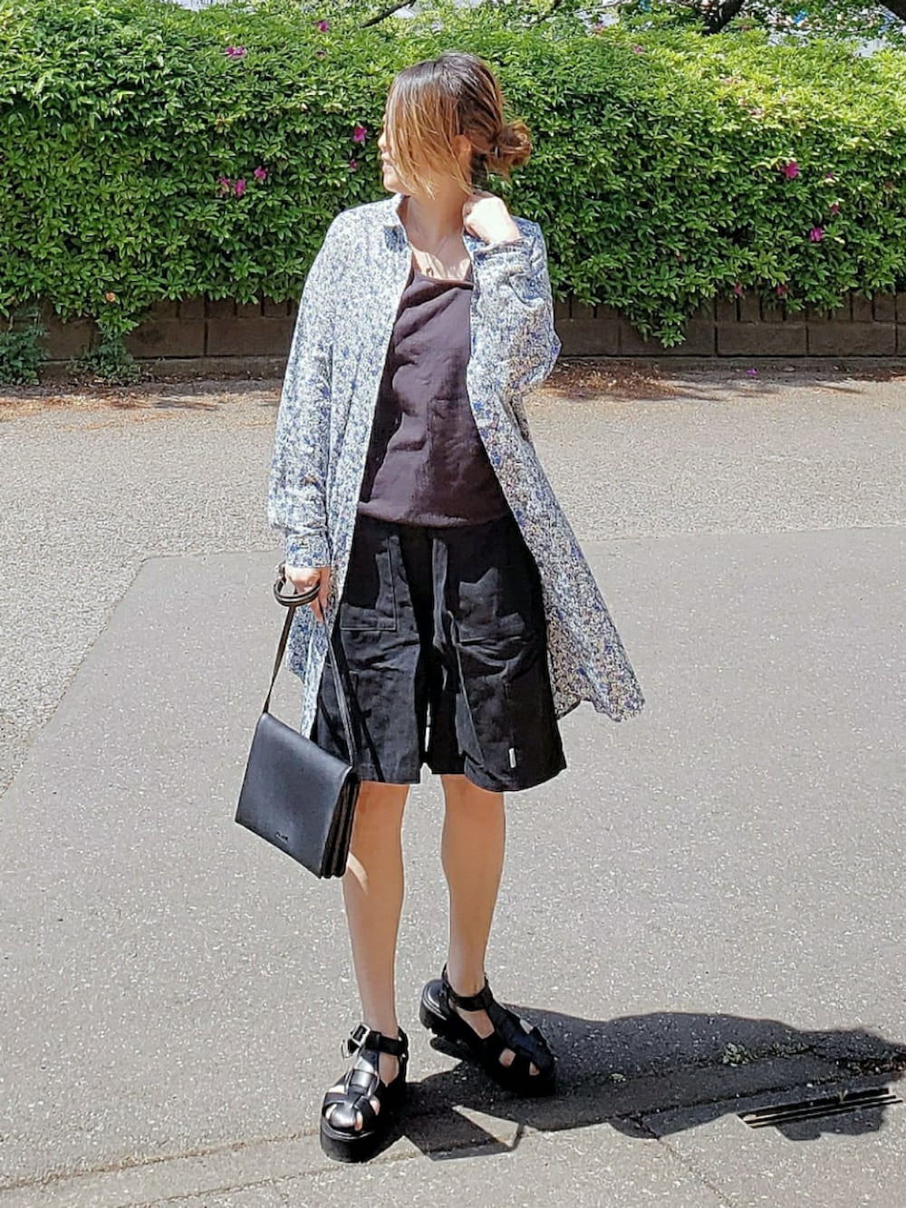 ブルー系のシャツワンピース、ブラック系のパンツ、ブラック系のサンダルを着用したレディースの春コーディネートの2枚目の写真