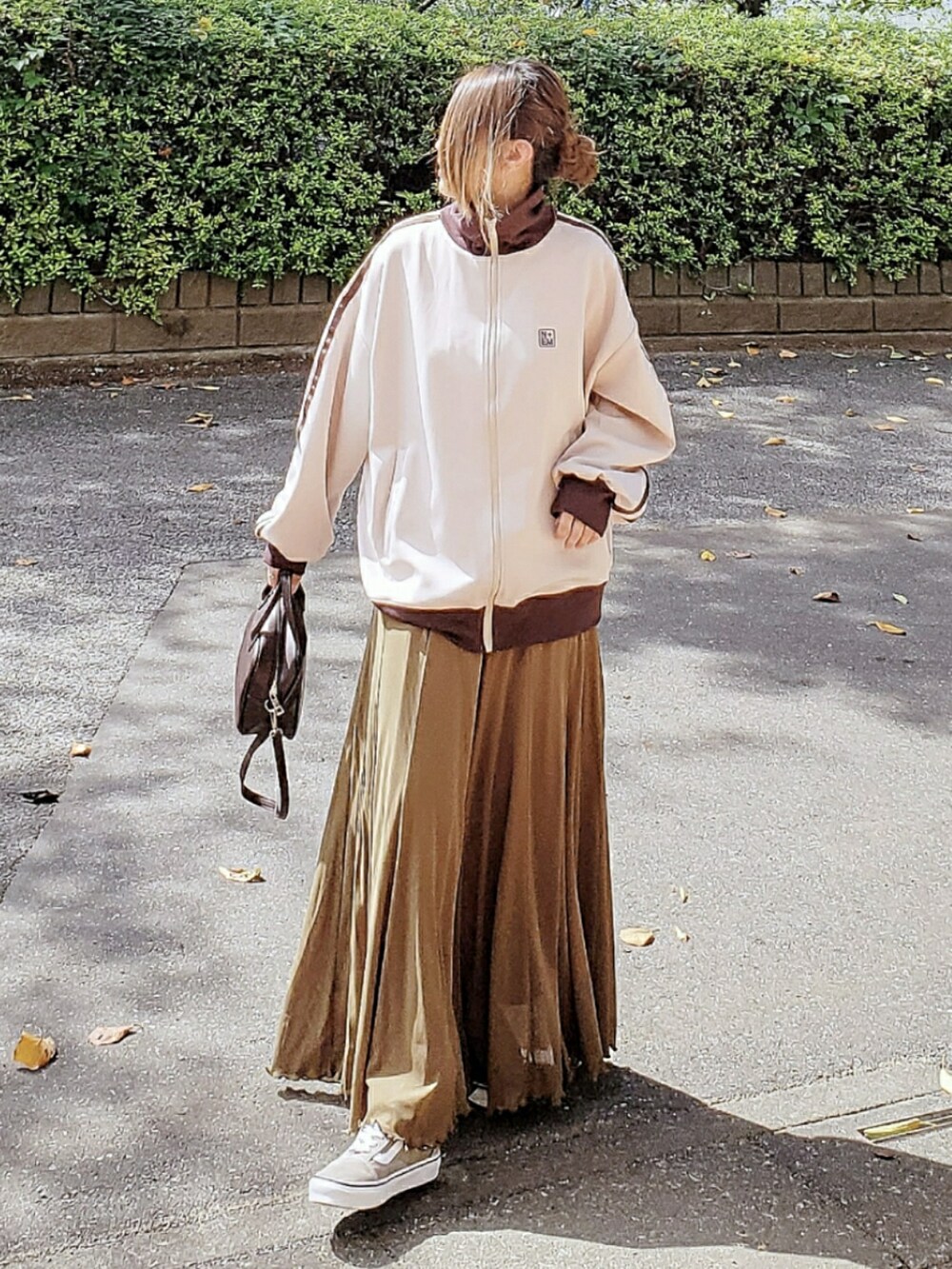 ベージュ系のスウェット、グリーン系のスカート、ブラウン系のボストンバッグを着用したレディースの秋コーディネートの3枚目の写真