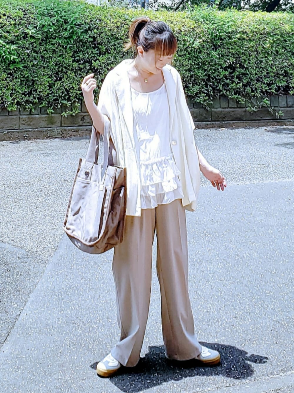 ホワイト系のテーラードジャケット、ホワイト系のキャミソール、ベージュ系のパンツを着用したレディースの夏コーディネートの3枚目の写真