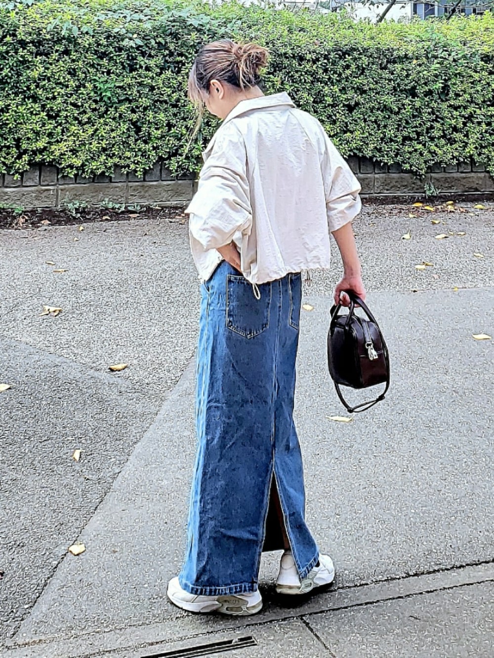 グレー系のナイロンジャケット、ブルー系のデニムスカート、ホワイト系のTシャツ/カットソーを着用したレディースの秋コーディネートの2枚目の写真