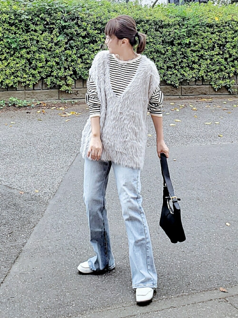 グレー系のベスト、ブラック系のTシャツ/カットソー、ブルー系のデニムパンツを着用したレディースの秋コーディネートの2枚目の写真