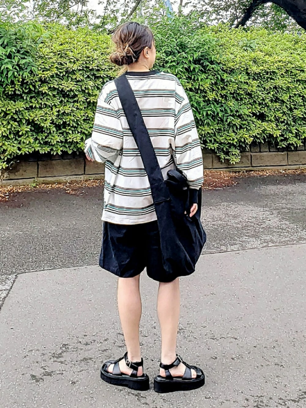 ブラック系のショルダーバッグ、ホワイト系のTシャツ/カットソー、ブラック系のパンツを着用したレディースの春コーディネートの4枚目の写真