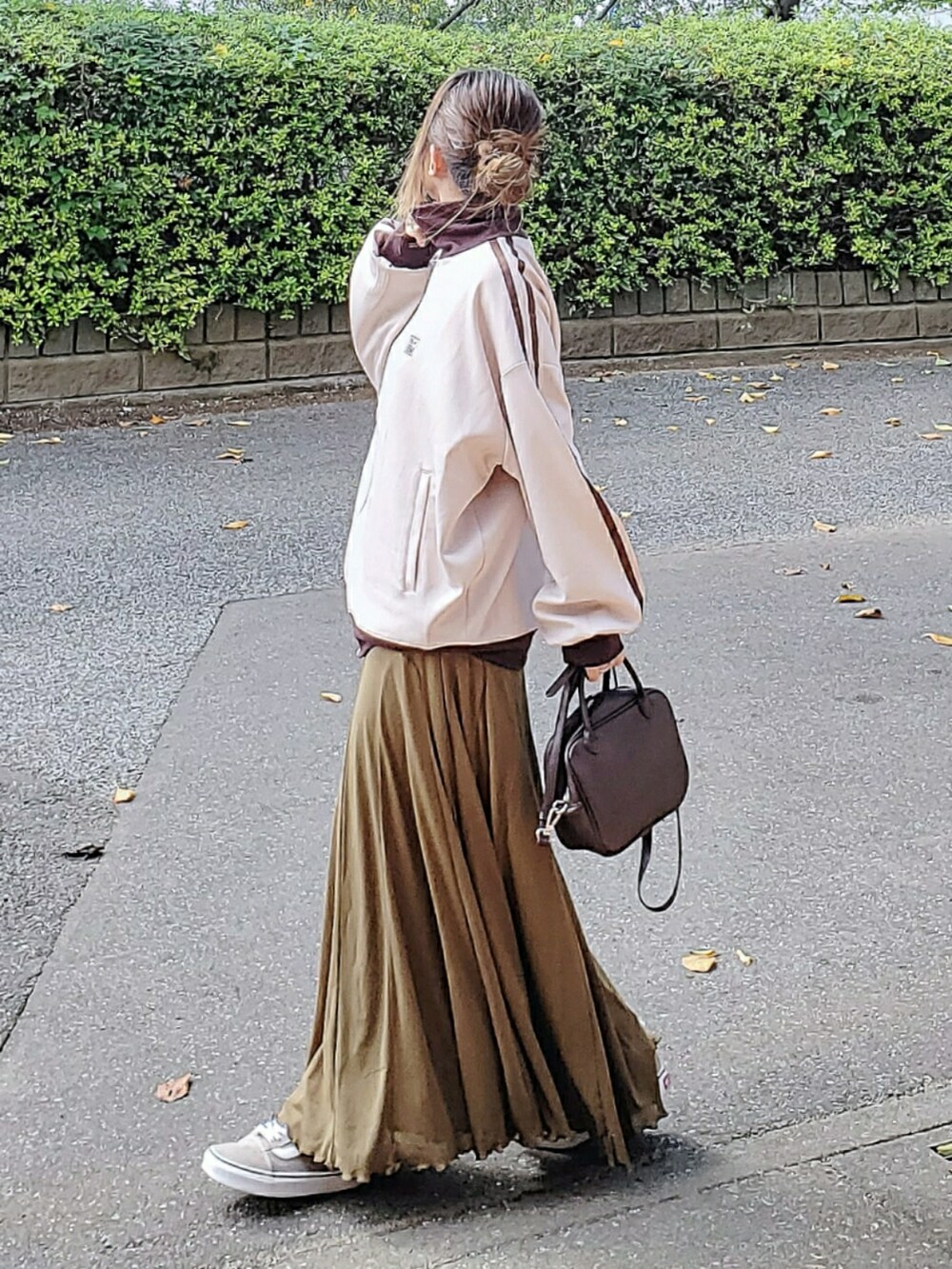 ベージュ系のスウェット、グリーン系のスカート、ブラウン系のボストンバッグを着用したレディースの秋コーディネートの2枚目の写真