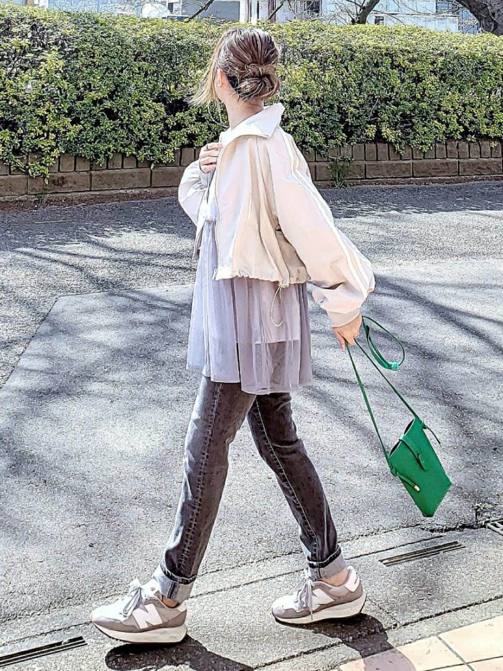 グレー系のナイロンジャケット、グレー系のキャミソール、グレー系のデニムパンツを着用したレディースの春コーディネートの2枚目の写真